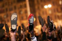 Anti-government protesters raise their shoes after a speech by Egyptian President Hosni Mubarek February 10, 2011 in Cairo, Egypt
