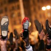 Anti-government protesters raise their shoes after a speech by Egyptian President Hosni Mubarek February 10, 2011 in Cairo, Egypt