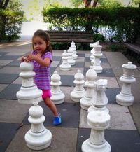 Child playing with large chess pieces