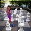 Child playing with large chess pieces