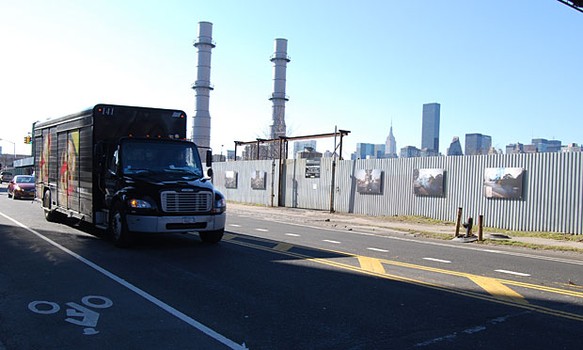 The show's six photographs line a corrugated fence at the junction in front of a Bridge Preventative Maintenance Storage Facility.