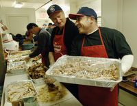 Rich Padula (R) holds a tray of carved turkey beside John Feeney (L) during Thanksgiving preparations at the Bowery Mission 23 November 2005 in New York. Founded in 1879, the facility is the third old