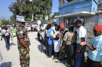 UN police patrol as people wait in line during the distribution of humanitarian aid in Port au Prince on March 11, 2010. President Barack Obama said Wednesday that Haiti's plight was still 'dire' afte
