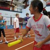 A girl lines up to run carrying a baton wearing a PS107 tshirt