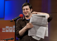 Eugene Mirman holds the full-page attack ad against Time Warner Cable he placed in The Greenpoint Gazette.