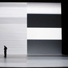 A man looks at another screen (his phone) while in the installation.