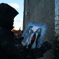 A painter from Colossal Media dangles 150 feet above the Soho streets, painting part of a 6-story Adidas ad.