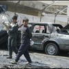 In Baghdad, Iraqi children walk past wrecked cars, February 2007