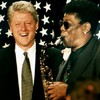 Former president Bill Clinton laughs as Clarence Clemons plays a rendition of the presidential tune 
