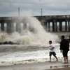 People walk along a sand-swept beach at Coney Island following heavy rain and winds from Hurricane Irene on August 28, 2011 in the Brooklyn borough of New York City. 