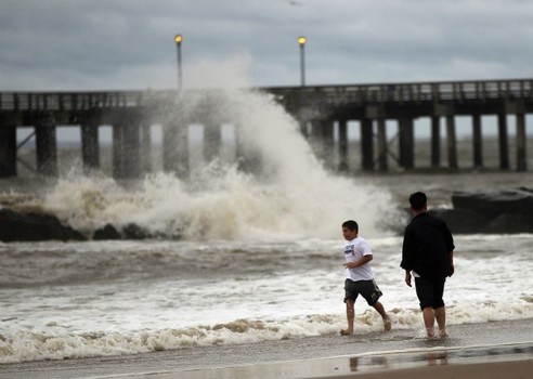 People walk along a sand-swept beach at Coney Island following heavy rain and winds from Hurricane Irene on August 28, 2011 in the Brooklyn borough of New York City. 