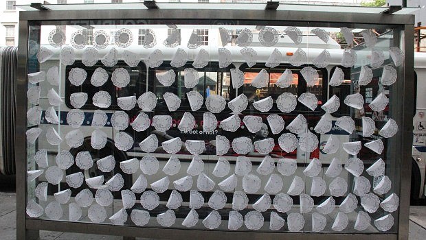 Between Eighth and Ninth Avenues, doilies are taped to a bus stop.