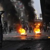 Egyptian riot police gather near burning tires as a demonstrator throws an object towards them during a protest in Cairo, Egypt on January 26, 2011
