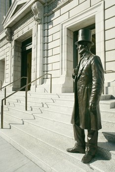 A bronze statue of Abraham Lincoln. The 77th Street entrance  has improved accessibility for school groups and visitors with disabilities, and illumination to highlight the features at night.