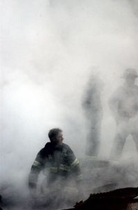 This US Navy photo released 17 September, 2001, shows a firefighter emerging from the smoke and debris of the World Trade Center September 14, 2001. 