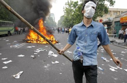 A police motorcycle burns behind a supporter of Iranian presidential candidate Mir Hossein Mousavi in June 2009