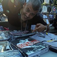 Joe Conzo Jr. at a hip-hop event in Crotona Park; posing with his book of Bronx photos