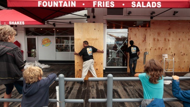 Children watch workers remove the plywood from the front windows of the Johnny Rocket's at the South Street Seaport just hours after Hurricane Irene blew through the city August 28, 2011.