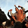 Men who have recently arrived from Libya celebrate at the border while waiting to be assigned to buses to take them to a transit camp on February 26, 2011 in Ras Jdir, Tunisia