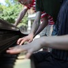 Three high school students playing a piano in Abe Lowenthal park in lower East Side in Manhattan waiting for a concert to begin on Make Music New York Day