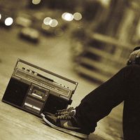 person with sneakers sitting next to a boom box