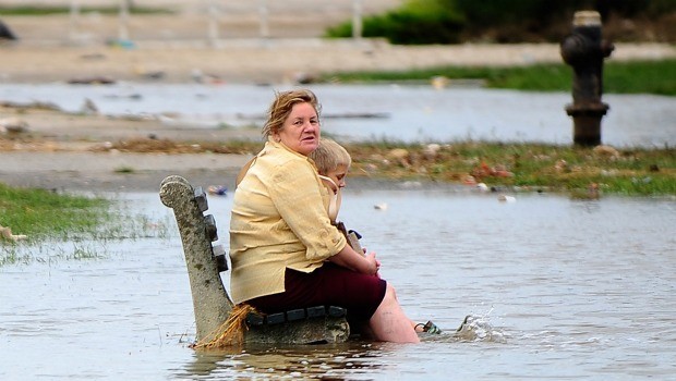 A woman and a child sit on a public bench amid floodwater on Rockway Beach after Hurricane Irene swept through New York City on August 28, 2011.