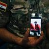 Iraqi Army Cpl. Saif holds a phone displaying a screenshot from a video released by the Islamic State group that shows his brother, in Irbil, Iraq. 