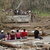 People sit on both sides of a destroyed bridge that crossed over the San Lorenzo de Morovis river, in the aftermath of Hurricane Maria, in Morovis, Puerto Rico, Wednesday, Sept. 27, 2017.