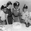Portrait of a group of children at birthday party where one is about to cut the cake, upon which is written 'Happy Birthday Margaret,' 1959.