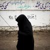 An Afghan resident walks past a graffiti slogan against the presidential election in the northwestern city of Herat 