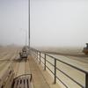 The boardwalk stretches off into the fog at Beach 81st Street in The Rockaways as a bulldozer spreads sand. coastcheck