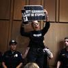 A protester stands on a chair and shouts as U.S. Capitol Police remove her during testimony by Supreme Court nominee, Brett Kavanaugh.