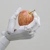 A robot holds an apple. 