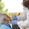 Lab technician James Donald, right, uses a nasal swab to test Hugo Marti for COVID-19, Tuesday, July 28, 2020, at the AHEPA Apartments in Miami.