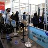 People with masks and bags line up before going through TSA security at LaGuardia Airport.