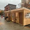 A man constructs a door to an outdoor dining shelter in Brooklyn.