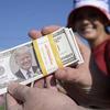 Kevin Miltenberger hands out imitation money with the likeness of President Donald Trump before a campaign rally at the Ocala International Airport, Friday, Oct. 16, 2020, in Ocala, Fla. 