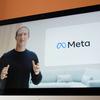 Mark Zuckerberg is featured on a screen. Stands with open hands, mid speech. Beside him, a screen shows the logo for Meta.