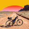 A lone mountain bike on a dirt road in the desert with a stylized rising Sun in the background. 