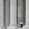 This Oct. 7, 2014, file photo shows a police officer dwarfed amid the marble columns of the U.S. Supreme Court in Washington.