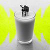 I tiny cow flouting on top of a full glass of milk.