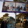 Afghan women by bread and a man walks by an election poster as the UN-backed Independent Election Commission (IEC) comes out with their long awaited results on October 19, 2009 in Kabul, Afghanistan.