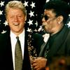 Former president Bill Clinton laughs as Clarence Clemons plays a rendition of the presidential tune 