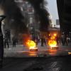Egyptian riot police gather near burning tires as a demonstrator throws an object towards them during a protest in Cairo, Egypt on January 26, 2011