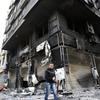 A man walks past a burnt-out building in the Northern city of Latakia, some 350 km northwest Damascus on March 27, 2011. 