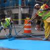 Maurice Bonin sprays blue paint and Gillie Etnel smooths it down on Broadway in Times Square.