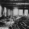 An officer stands at the Asch Building’s 9th floor window after the Triangle fire. Sewing machines, drive shafts, and other wreckage of the Triangle factory fire are piled in the center of the blaze-s