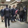 Amtrak police watch as passengers make their way to the track to board the first train to leave Penn Station after delays caused by a stuck train, Friday, April 14, 2017.
