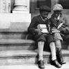  In 1933 in Harlem, New York, two black children seated on the sidewalk look at their schoolbooks. One of the books concerns American history.