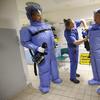  A nurse helps a doctor and nurse take off their isolation suits following a demonstration for the media of ebola treatment capabilities at Station 59 at Charite hospital on August 11, 2014 in Berlin.